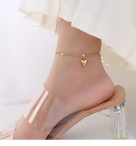 Close-up of a 18k gold plated heart anklet with zircons worn with transparent heels