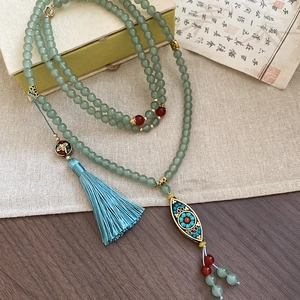 Detail of vintage beaded necklace with light green jade beads and a silk tassel pendant