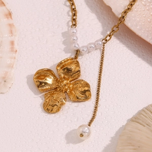 Detailed view of 18K gold plated flower pendant with pearls on a moist white shell surface