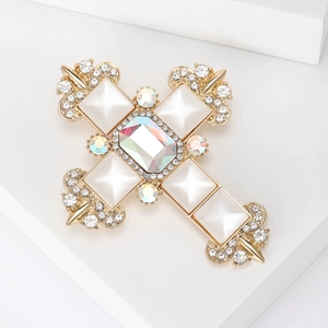 Detailed macro view of Baroque gold cross brooch with pearlescent gems and rhinestones