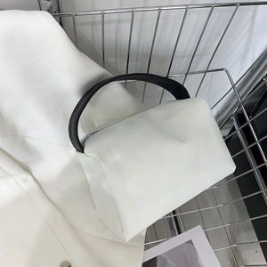 Minimalist white tote bag with black flat handles on white suit and metal grid