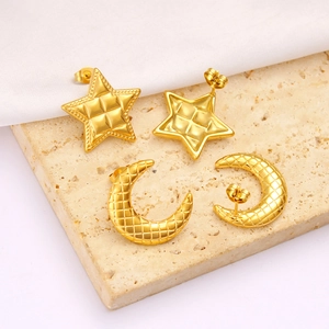 Detail of star and moon stud earrings featuring golden quilted texture on marble