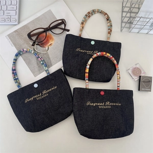 Close-up of three mini denim tote bags with colorful beaded handles and embroidery