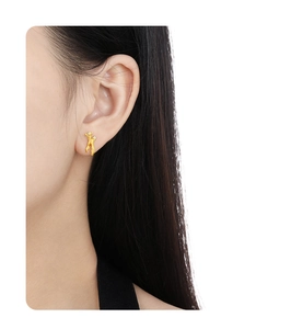 Macro shot of gold irregular figure earring with small inset diamonds on model ear