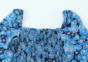 Detailaufnahme von Karree-Ausschnitt und gesmoktem Blumenstoff an Kleid mit Puffärmeln