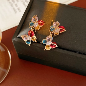 Macro detail of vintage gold-plated butterfly earrings with multi-colored zircon stones