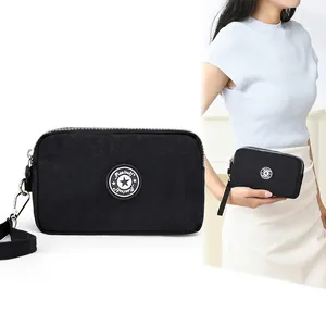 Zwarte nylon mini telefoontas met drie ritsen en een sterlogo op de handriem
