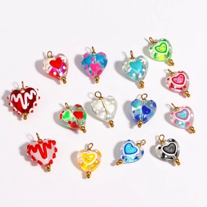 Macro shot of colorful glass heart charms with gold loops for DIY jewelry making