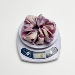 Tie-dye satin hair scrunchie shown on a digital scale weighing approximately 10.9 grams