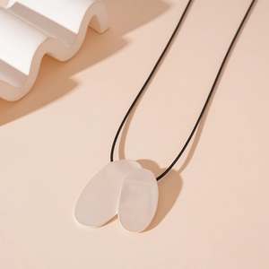 Detailed view of silver matte irregular oval pendants on a sleek black cord necklace