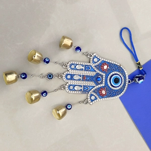 Macro shot of silver Hamsa Hand wall hanging with blue evil eye charms and metal bells
