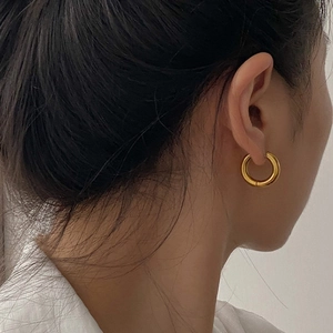 Close-up of minimalist chunky 18K gold-plated stainless steel hoop earrings on model