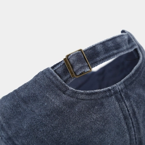 Detailed close-up of dark blue cotton cap with adjustable bronze metal slider buckle