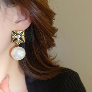 Detail of vintage gold square stud earring with rhinestones and large pearl on model