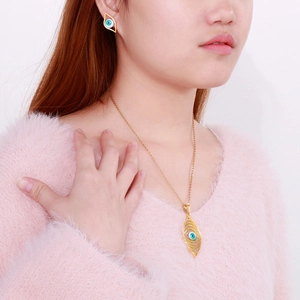 Detail of bohemian gold devil eye necklace and earrings set worn on a model