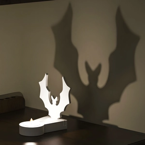 Detail showing bat-shaped candle holder casting a large shadow on the wall for Halloween