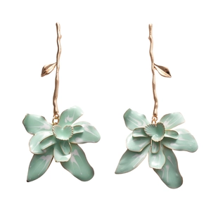 Elegant gold flower earrings with green petals and white texture on white background