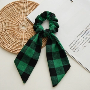 Detail of green and black buffalo plaid scrunchie with long ribbon on a rustic mat