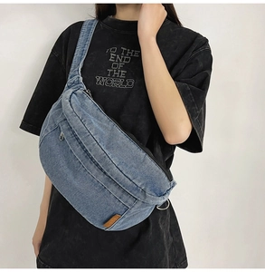 Detail of blue denim crossbody bag featuring durable zippers and vintage brown leather patch