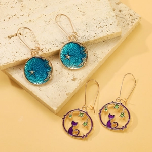 Macro detail of planet cat and starry night enamel earrings on beige stone display