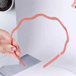 Detailed view of pink wavy plastic headband showing anti-slip inner teeth and smooth finish