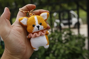 Close-up of handmade crochet Corgi puppy keychain with orange and white yarn details