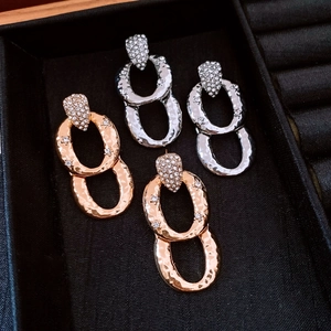 Close-up of hammered gold and silver oval drop earrings with sparkling rhinestones detail