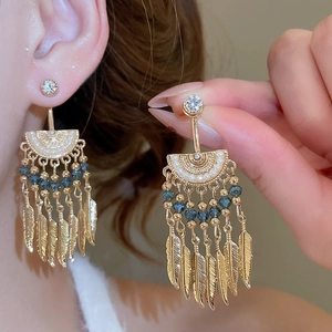 Detail of French vintage crystal tassel earrings featuring gold feather charms on a model