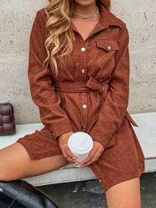 Detailed texture of brown corduroy shirt dress with metal buttons and waist belt