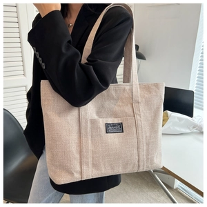 Detailed view of natural beige canvas tote bag with front pocket and fashion label