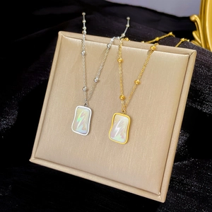 Titanium steel necklaces in gold and silver with iridescent square pendants on black velvet