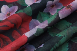 Détail de l'imprimé floral sur tissu en soie noire avec roses rouges et violettes