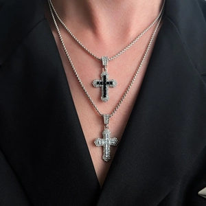 Detail van gelaagde kruishangers met zirkonia inleg op een stijlvolle zwarte blazer achtergrond