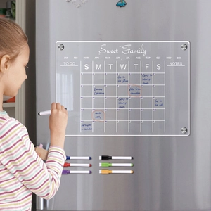 Girl writing on a magnetic acrylic weekly planner on a stainless steel fridge
