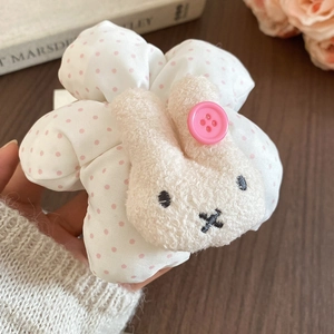 Detail of pink polka dot fabric hair tie featuring a plush bunny and button accent