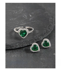 Close-up of heart-shaped green zircon silver ring and stud earrings set on black stone