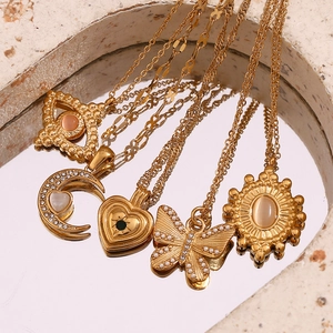 Detail showing five gold-plated necklaces with opal pendants on a reflective mirror