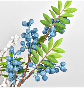 Close-up of artificial blue berry branches with green feathery leaves for holiday decor