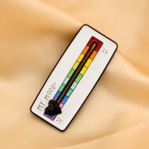 Detail showing an interactive rainbow mood tracker enamel pin with a sliding black heart slider