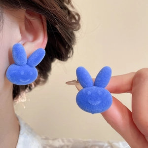 Detailed view of bright blue flocked bunny stud earrings with matte velvet texture