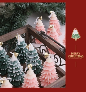 Festive Christmas tree shaped candles in green and pink with small golden bells