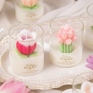 Macro shot of tulip-shaped soy wax scented candle in a glass cup on an embossed tray
