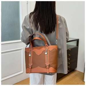 Close-up of caramel leather tote bag with vertical zippers and litchi texture
