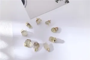 Set of raw yellow crystal pendants with gold edges on white background and floral shadows