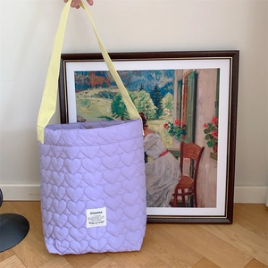 Detail of lavender heart-quilted shoulder bag with contrasting yellow strap and logo
