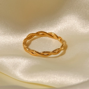 18K gold plated stainless steel twisted rope ring on elegant beige satin fabric