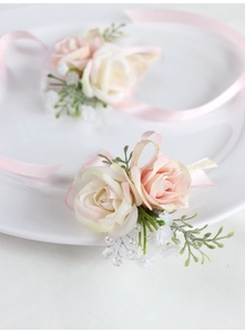 Dettaglio del fiore all'occhiello con rosa rosa finta, nastri di seta e perle da sposa