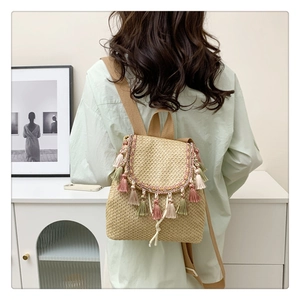 Detail of straw bucket bag with multi-color tassels worn as a backpack on a model