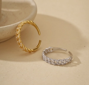 Detailed close-up of adjustable chain weave rings in gold and silver with white zircons