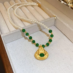 Detail der Jade-Halskette mit goldenem Buddha und weißen Perlen in Schmuckschatulle